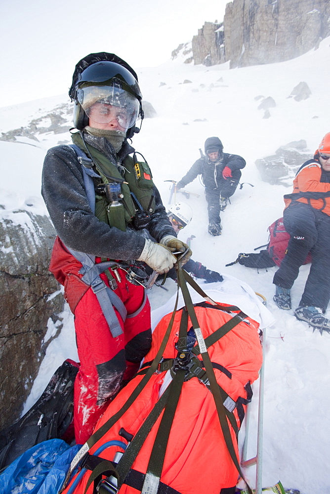 A Navy Sea King helicopter crew and mountain rescue team members treat a seriously injured walker who had fallen 250 , Cumbria, England, United Kingdom, Europe