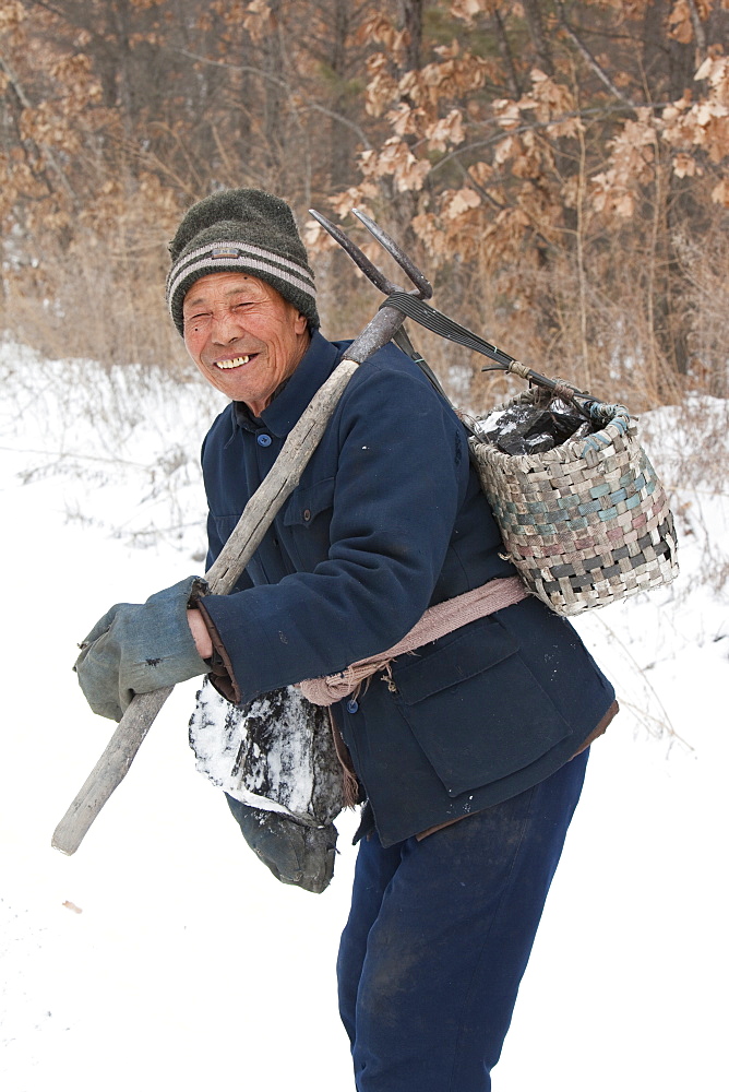 A Chinese peasant collects coal that has fallen from lorries taking coal from an open cast coal mine to power plants near Heihe on the Chinese Russian border, Heilongjiang, China, Asia