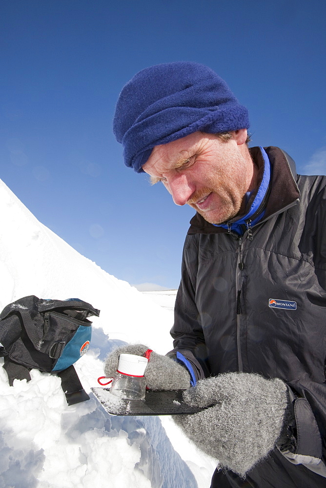 A member of the Scottish Avalanche Information Service looks at snow crystals to help assess avalanche risk on  Cairngorm in the Cairngorm National Park in Scotland, United Kingdom, Europe