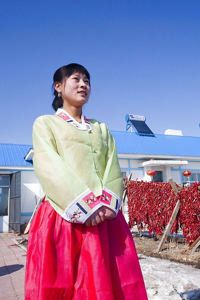 Zhang Xinru an ethnic South Korean emigre poses in front of her new house built by the local communist party with solar panels on the roof, near Suihua city, northern China, Asia