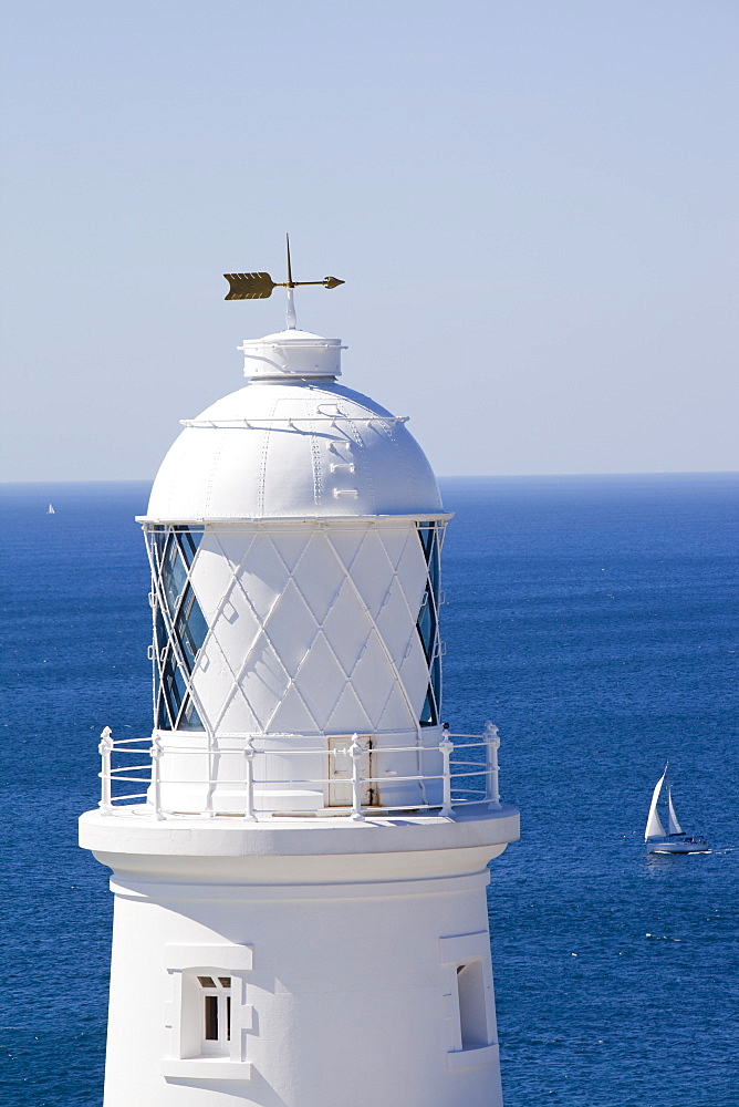 A sailing boat sails past Pendeen Watch lighthouse near St. Just in Cornwall, England, United Kingdom, Europe