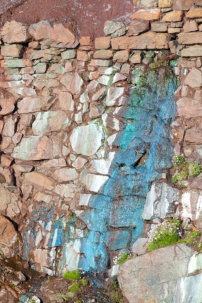 Sea cliffs stained green from copper deposits leaching from the old Geevor Tin Mine near St. Just in Cornwall, England, United Kingdom, Europe