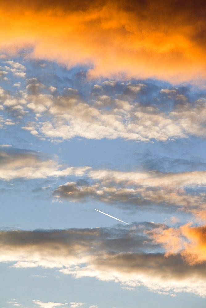 A plane flying through clouds at sunset over Ambleside, Cumbria, England, United Kingdom, Europe