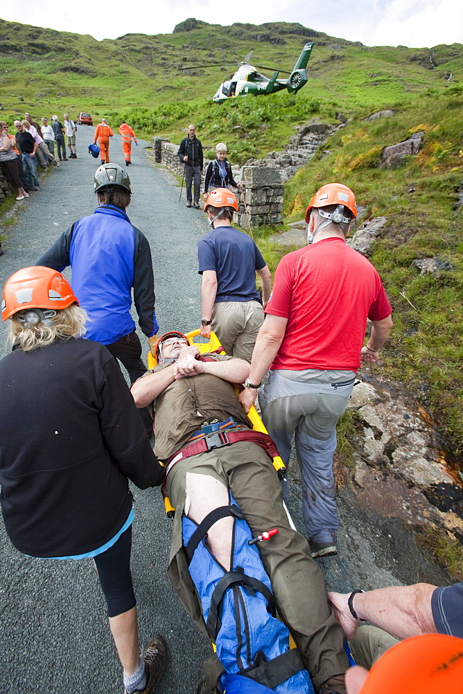 Paramedics from the Great North Air Ambulance and members of Langdale/Ambleside Mountain Rescue Team treat an injured man who fell into Wrynose Beck, before transferring him to hospital via helicopter. Lake District, Cumbria, England, United Kingdom, Europe