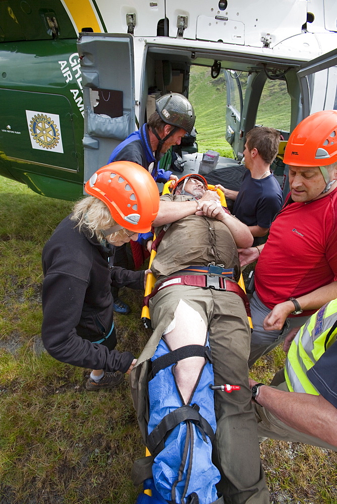 Paramedics from the Great North Air Ambulance and members of Langdale/Ambleside Mountain Rescue Team treat an injured man who fell into Wrynose Beck, before transferring him to hospital via helicopter. Lake District, Cumbria, England, United Kingdom, Europe