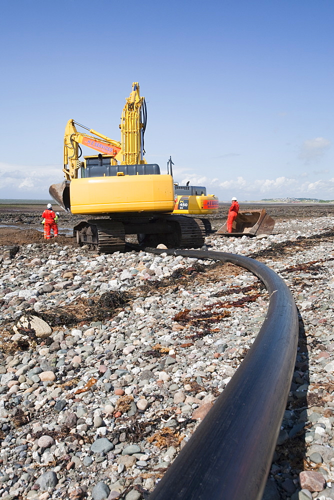 Construction workers installing a power cable on the foreshore of the Solway Firth near Workington, Cumbria, England, United Kingdom, Europe