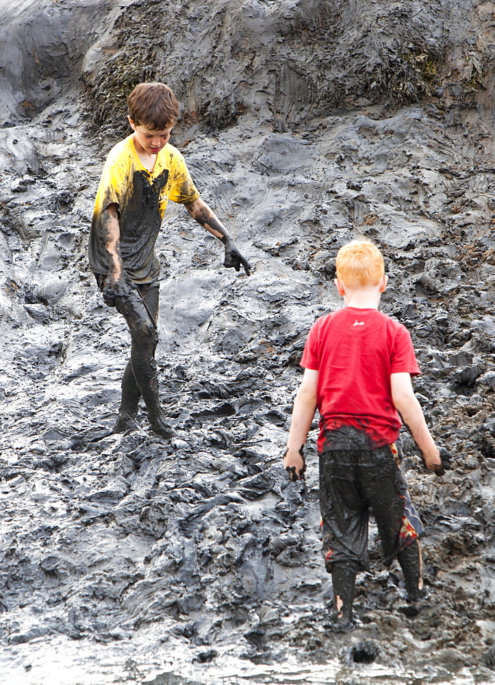 Children playing in a muddy creek at Blakeney, North Norfolk, England, United Kingdom, Europe