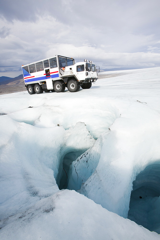 A twenty ton ice explorer truck owned and run by Arngrimur Hermannsson ( Arni), next to a sink hole for meltwater (moulin), Langjokull ice cap, Iceland, Polar Regions