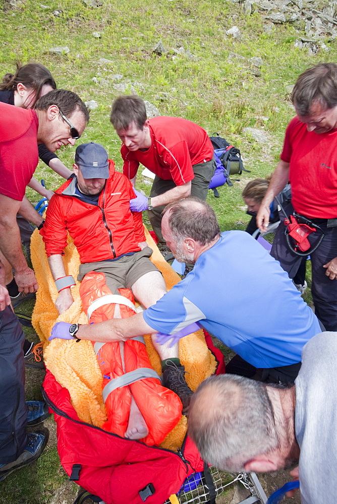 A man with a leg injury is treated by members of the Langdale Ambleside Mountain Rescue Team before being evacuated by air ambulance, above Grasmere, Lake District, Cumbria, Engalnd, United Kingdom, Europe