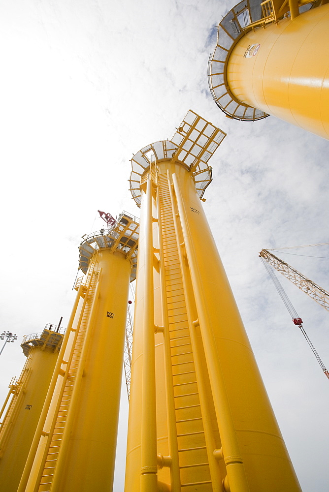 The yellow transition pieces that will hold the tower and turbine, that fit onto the monopile to hold the structure to the sea bed, Walney Offshore Wind Farm, Barrow in Furness, Cumbria, England, United Kingdom, Europe