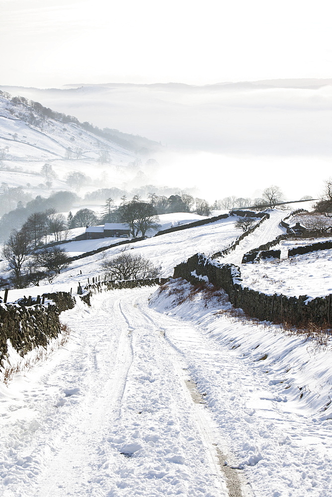 Kirkstone Pass snowed up in winter looking down towards Ambleside shrouded in valley mist, Lake District, Cumbria, England, United Kingdom, Europe