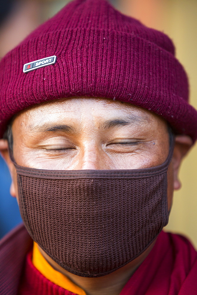 A Buddhist monk wearing a face mask against the appalling Kathmandu air pollution at Boudanath, Kathmandu, Nepal, Asia