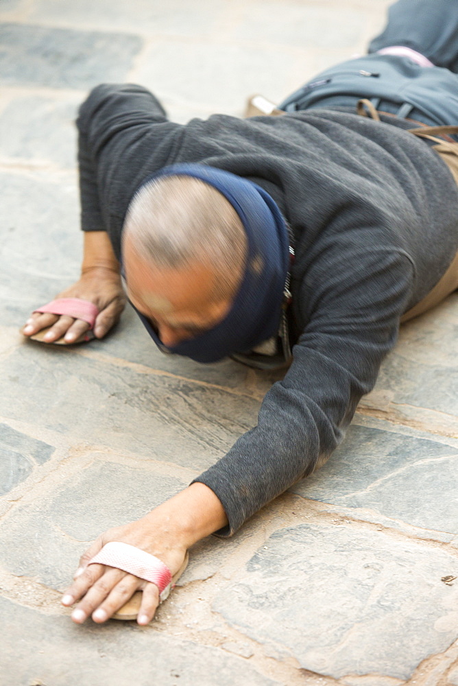 A Nepalese Buddhist prostrating himself around the Buddha Stupa in Kathmandu, Nepal, Asia