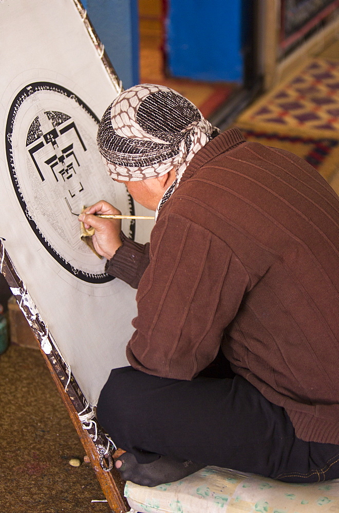 A Buddist artist painting a traditional Thanka painting at the Boudhanath Stupa, one of the holiest Buddhist sites in Kathmandu, Nepal, Asia