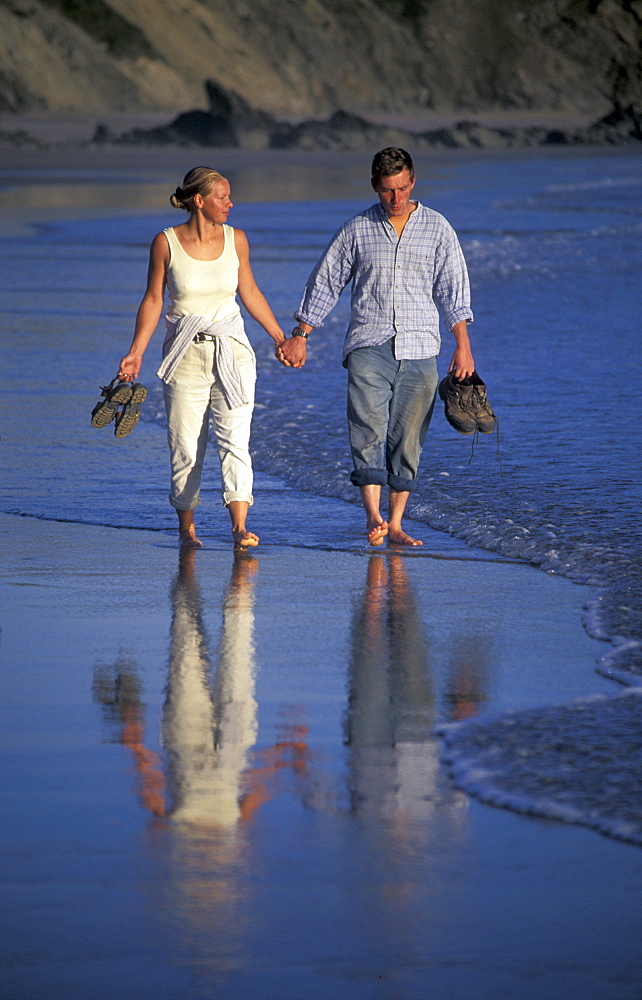 Couple walking at water's edge, Marloes Sands, West Wales, UK