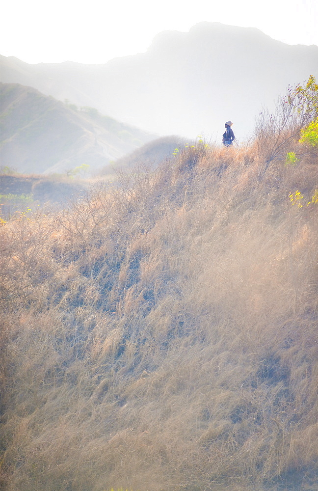 Country Side, Mountain Vilage, 03/04/2009. Landscape view from the road in the area of Praia on Sao Tiago Island, Cape Verde. Native woman standing on hill side in mid day. . Praia, Sao Tiago Island. Cape Verde