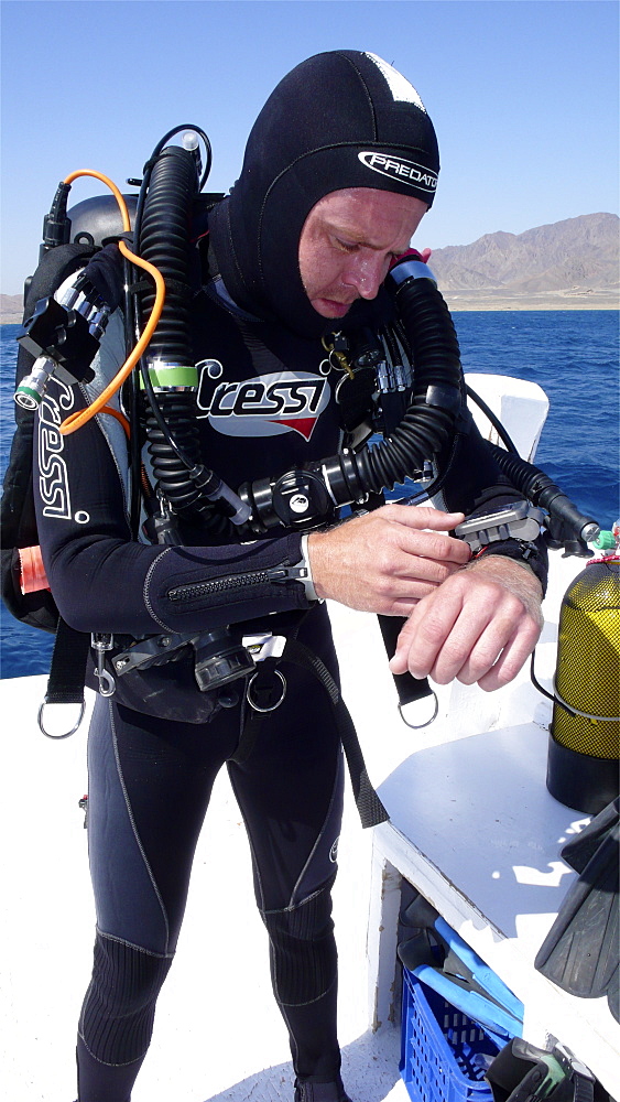 Diver on board dive boat checking equipment    