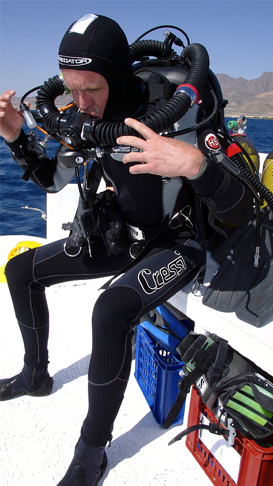 Diver on board dive boat checking equipment    