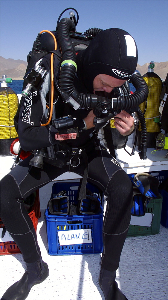 Diver on board dive boat checking equipment    