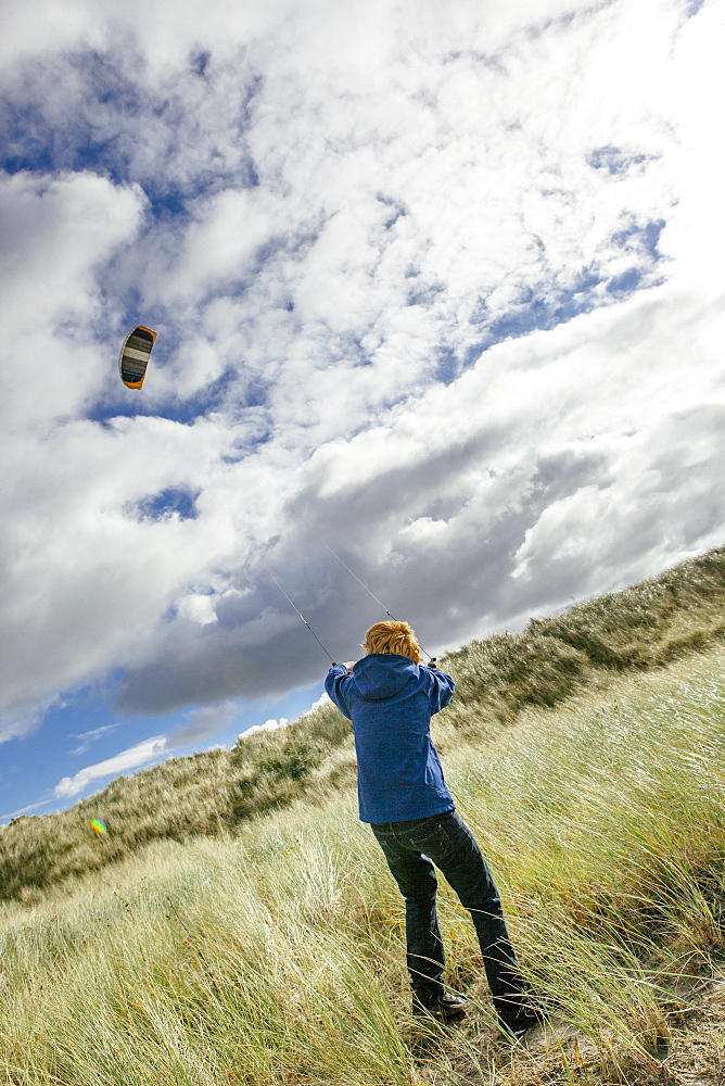 Young man flying kite, Schiermonnikoog, West Frisian Islands, Friesland, The Netherlands (Holland), Europe