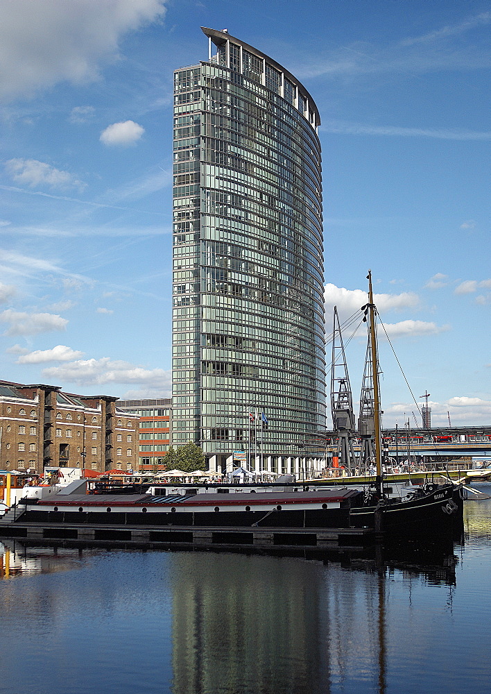 Set amongst period features of a Bygone West India Quay; including buildings boats and cranes.  The new Marriot Hotel stands majestically as part of the new 21st century skyline of Canary Wharf . London, England, UK