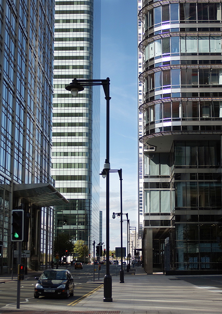 Car waits at traffic lights on Upper Bank St.  Dwarfed by the glass structures either side of the road, there is little happening on street level. London, England, UK