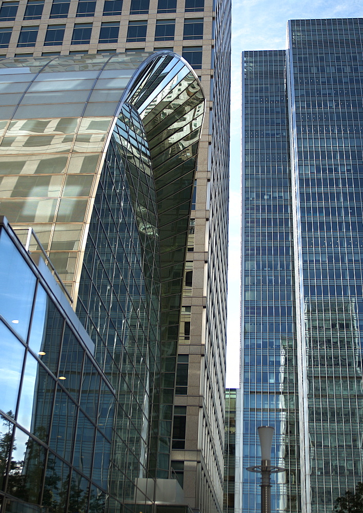 Looking up along Bank St. Canary Wharf, London you see a mosaic of glass and steel, blending well with the blue sky backdrop. London, England, UK