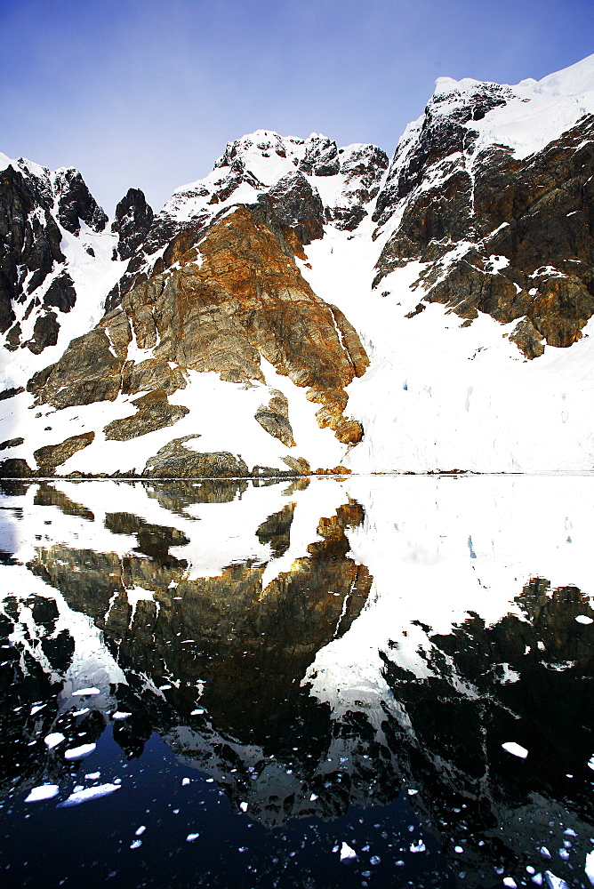 Reflections and snow covered mountains in Lemaire Channel in Antarctica.