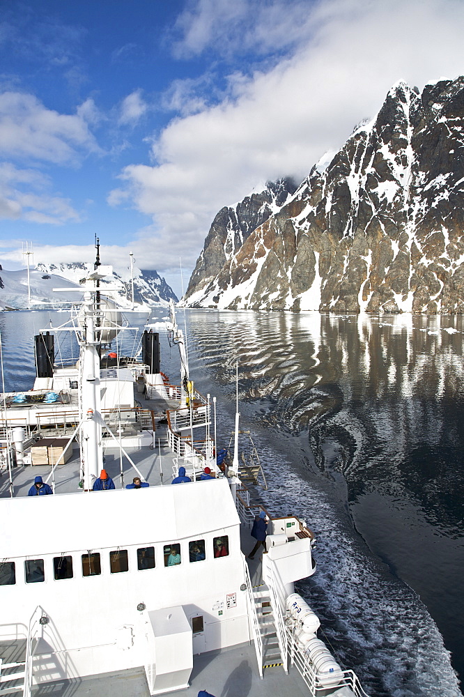 The Lindblad Expedition ship National Geographic Explorer transits Lemaire Channel in late evening light on the west side of the Antarctic peninsula in Antarctica