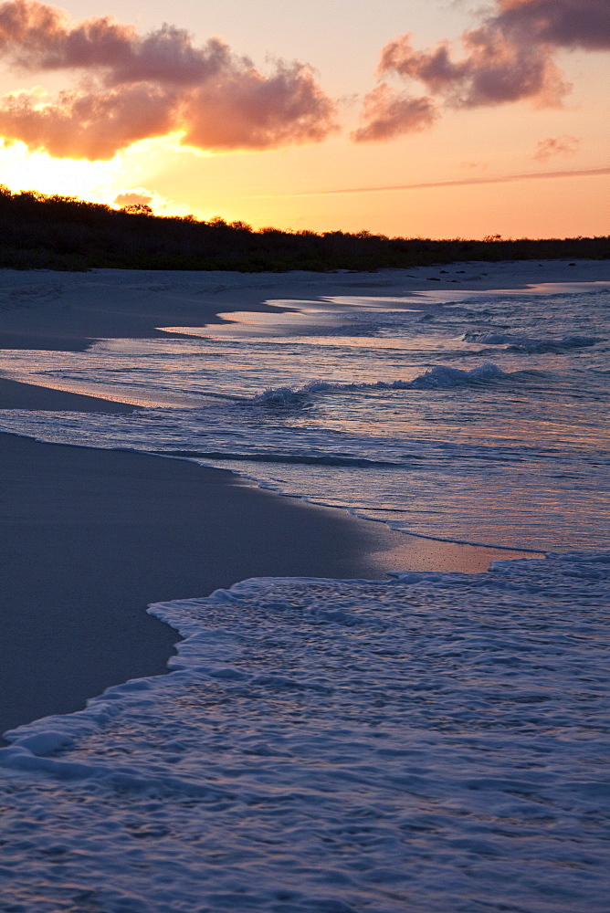 Waves washing onto the beach at sunset in the Galapagos Island Archipeligo, Ecuador. Pacific Ocean.