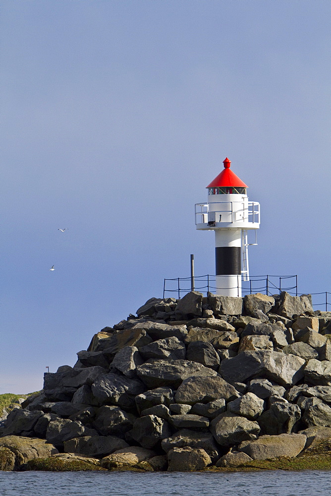 Lighthouse on the breakwall leading to the picturesque Norwegian fishing town of Reine in the Lofoton Island Group, Norway.