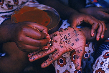 Lamu, Kenya. Swahili woman paints henna design on hand of a friend for Idd al Fitr festival.