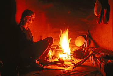 A young woman rests reflectively by a hearth in Almora India