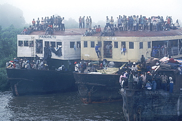 Passengers crowd the decks and roofs of three lead barges pushed up the Congo River by the boat Col. Ebeya.