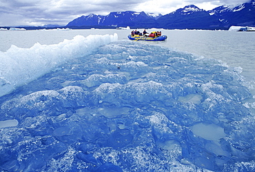 A raft makes its way past a small aqua blue icebergs on Alsek lake during a 12 day rafting trip down the Tatshenshini and Alsek rivers.