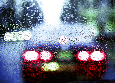 Tail lights of a car driving in the rain.