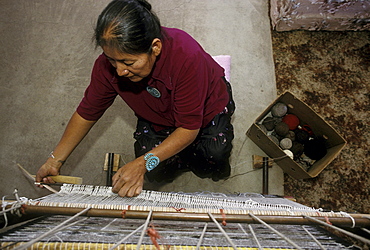 A Navajo woman weaves a rug in her home in Burnham, New Mexico on the Navajo Indian Reservation.