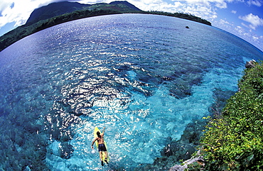 Mark Anders surfing, paddeling in the aqua blue warm water off the coast of Nagigia, Fiji. Nagigia is one of Fiji's many islands famous for its reef surfing.