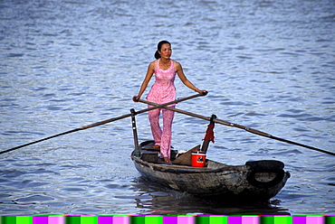 Woman ferry boat operator rows boat across river in Mekong Delta in the city of Cantho, Vietnam.