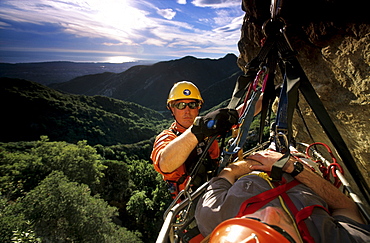 Steve McNeil tends a Search and Rescue stretcher carrying John Siekowski while training on Gibraltar Rock in Santa Barbara, California on January 18, 2003. The two are volunteer members of Santa Barbara County Search and Rescue. The view looks south over Rattlesnake Canyon to the Pacific Ocean beyond. (Photo by Kevin Steele, Aurora)