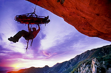 Shannon Black, silhouetted against the sunset sky, tends a Search and Rescue stretcher on the overhanging face of Gibraltar Rock in Santa Barbara, California on January 18, 2003.