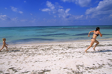 A little girl, Ruby Guy, chases her mother, Naomi Guy, on the white sand beach of Cayo Jutia, Pinar del Rio province, Cuba.  Cayo Jutia is a small island with uncrowded beaches that is popular with tourists and is part of the Las Colorados Archipelago in Western Cuba.