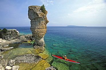 Bernadette Muhic-Georgi sea-kayaks past Flowerpot Island in Fathom Five National Marine Park, Georgian Bay, Lake Huron near Tobermory, Ontario, Canada.