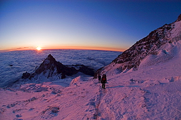 Sunrise brings light and warmth, as well as beautiful colors, to 12,000 feet on Mount Rainier's Emmons Glacier; Little Tahoma Peak rises behind.