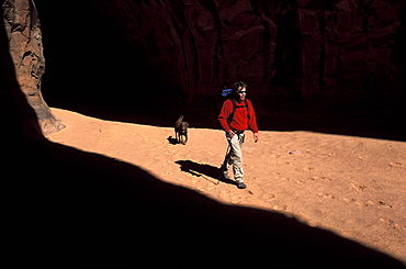 Todd Snyder and his canine companion walk through a swath of light somewhere around Lake Powell in Utah.