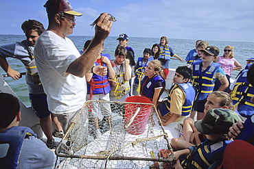 A former waterman and now a worker for the Chesapeake Bay Foundation demonstrates how to bait a crab pot for sixth grade students near Tangier Island, VA