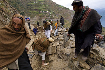 Pashtun men clear rocks from a landslide that is blocking the road to the Allai Valley, and preventing many  trucks    full of  earthquake survivors and their possessions from traveling back to their mountan villages, Battagram District, Pakistan's Northwest Frontier Province.  The region was one of the worst-hit by the October 2005 earthquake, and aftershocks and  heavy rains continue to trigger landslides, which have hampered reconstruction efforts and the return of earthquake survivors  to their mountain villages from the low altitude tent camps where many spent the winter.