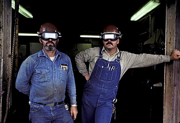 Two welders pose in the frame of a door.