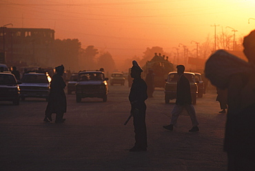 Setting sun highlights traffic and traffic cops in the center of Mazar-i-Sharif, Balkh Province, September 22, 2002. Mazar-i-Sharif  (also spelled Mazar-e Sharif) is the largest city in Northern Afghanistan, and is capital of the Balkh province.  It is an important city for Afghanistan's Shiite Muslims, who come to worship at the famous Blue Mosque.