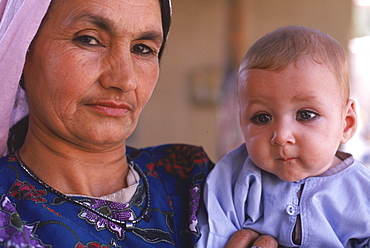 A Tajik woman holds a baby with kohl rimmed eyes, in the compound of an extended, traditional family in Mazar-i-Sharif, Balkh Province, September 25, 2002.  The Tajik are one of the larger ethnic groups in Afghanistan, second only to the Pashtun people.